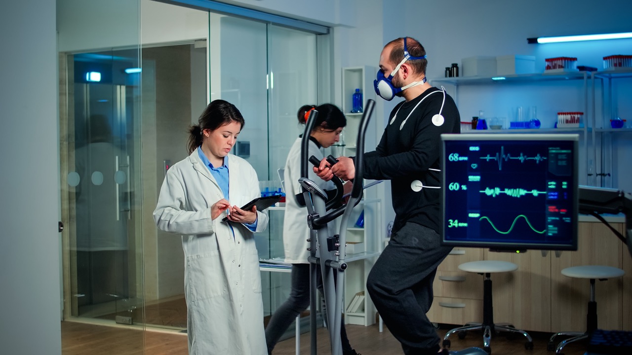 Sportsman with mask running on cross trainer in sports science laboratory